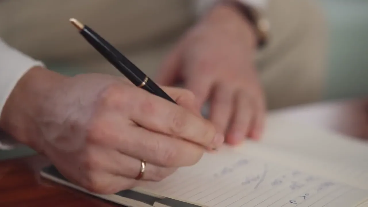 A person makes handwritten notes in a notebook.